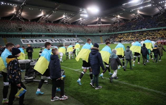 Varssavi Legia ja Kiievi Dinamo mängijad väljakule sammumas, Ukraina lipud õlgadel. Foto: Scanpix / Leszek Szymanski / EPA
